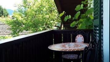 Eine kleine Terrasse im Freien mit einem runden Tisch und zwei Stühlen, umgeben von einem Holzgeländer.