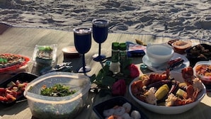 A beach picnic setup with food and drinks on a blanket, overlooking the ocean. - Well-appointed condo with a large lanai, outdoor kitchen and enclosed garage. (Naples)