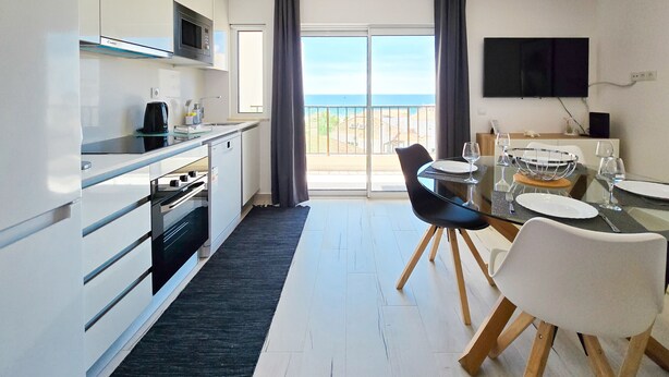 A modern kitchen with a dining area, large windows, and a flat-screen TV. - Apartment Praia Rocha Vista Mar Summer 2 (Portimão)