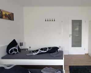 Un dormitorio moderno con una cama, un bolso a rayas blanco y negro, una toalla gris y un cuadro de un paisaje urbano.