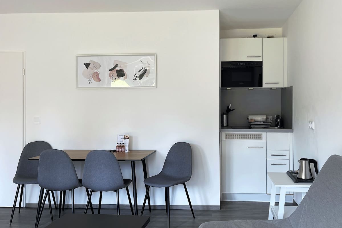 A compact living space with a dining area, kitchenette, and a gray sofa.