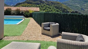 A patio with outdoor furniture, a swimming pool, and a view of mountains.