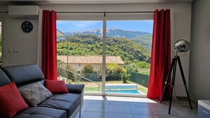 A modern living room with a sofa, a tripod, and a view of a pool and mountains.