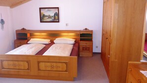 A bedroom with a wooden bed, bedside tables, a wardrobe, and a painting on the wall. - Vacation apartment no. 14 for 2 - 4 persons, approx. 100 m², 1 bedroom, living room, kitchen, bathroom (Bischofswiesen)