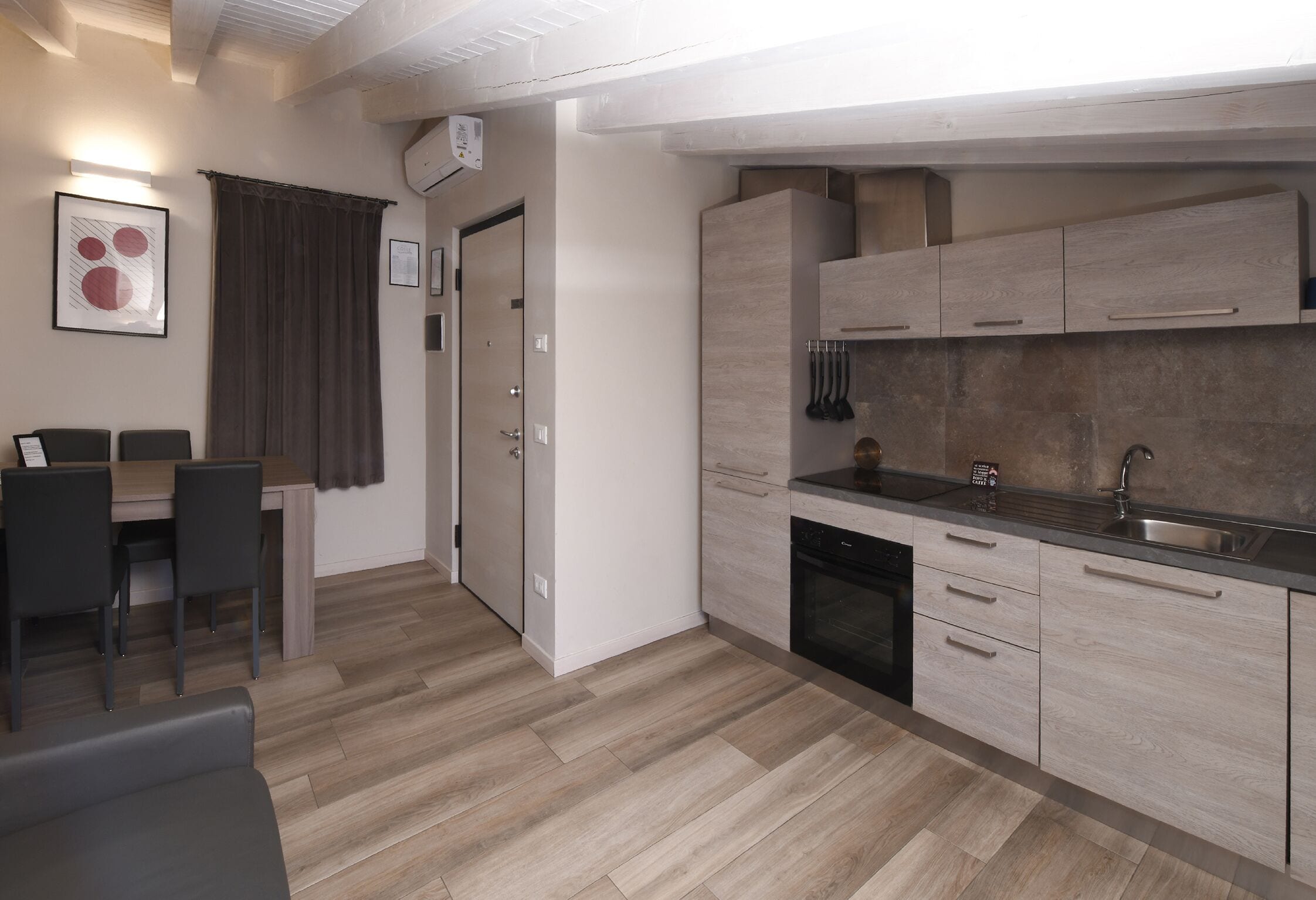 Eine moderne Küche mit hellen Holzschränken, einem eingebauten Backofen und einer Edelstahl-Spüle.