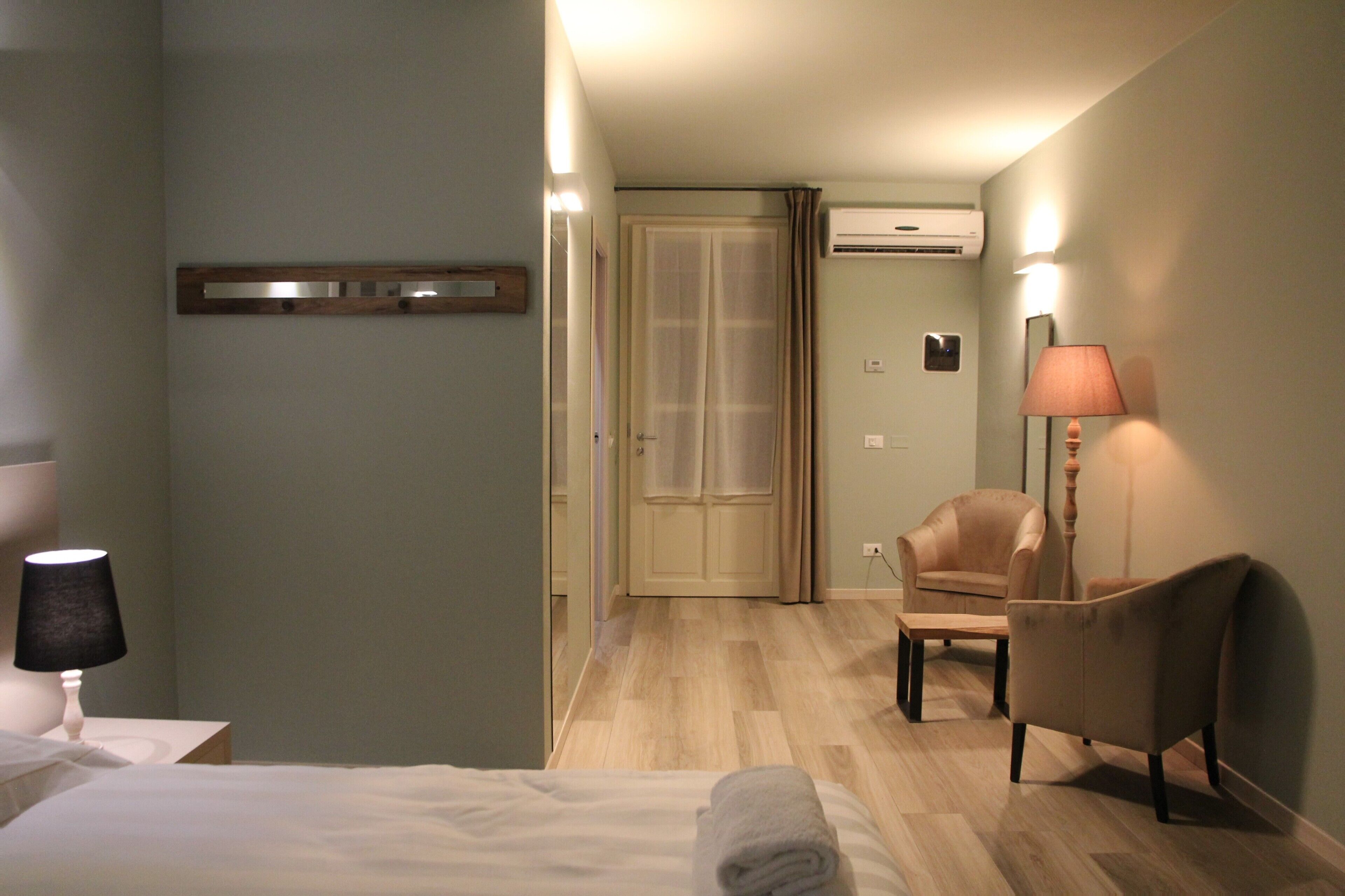 Una habitación de hotel con una cama, una silla, un escritorio, una lámpara y un equipo de aire acondicionado.