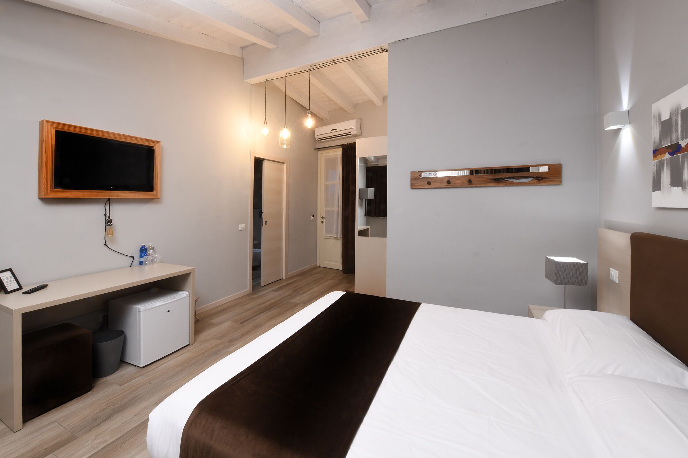 Habitación de hotel moderna con cama, escritorio, televisor y armario.