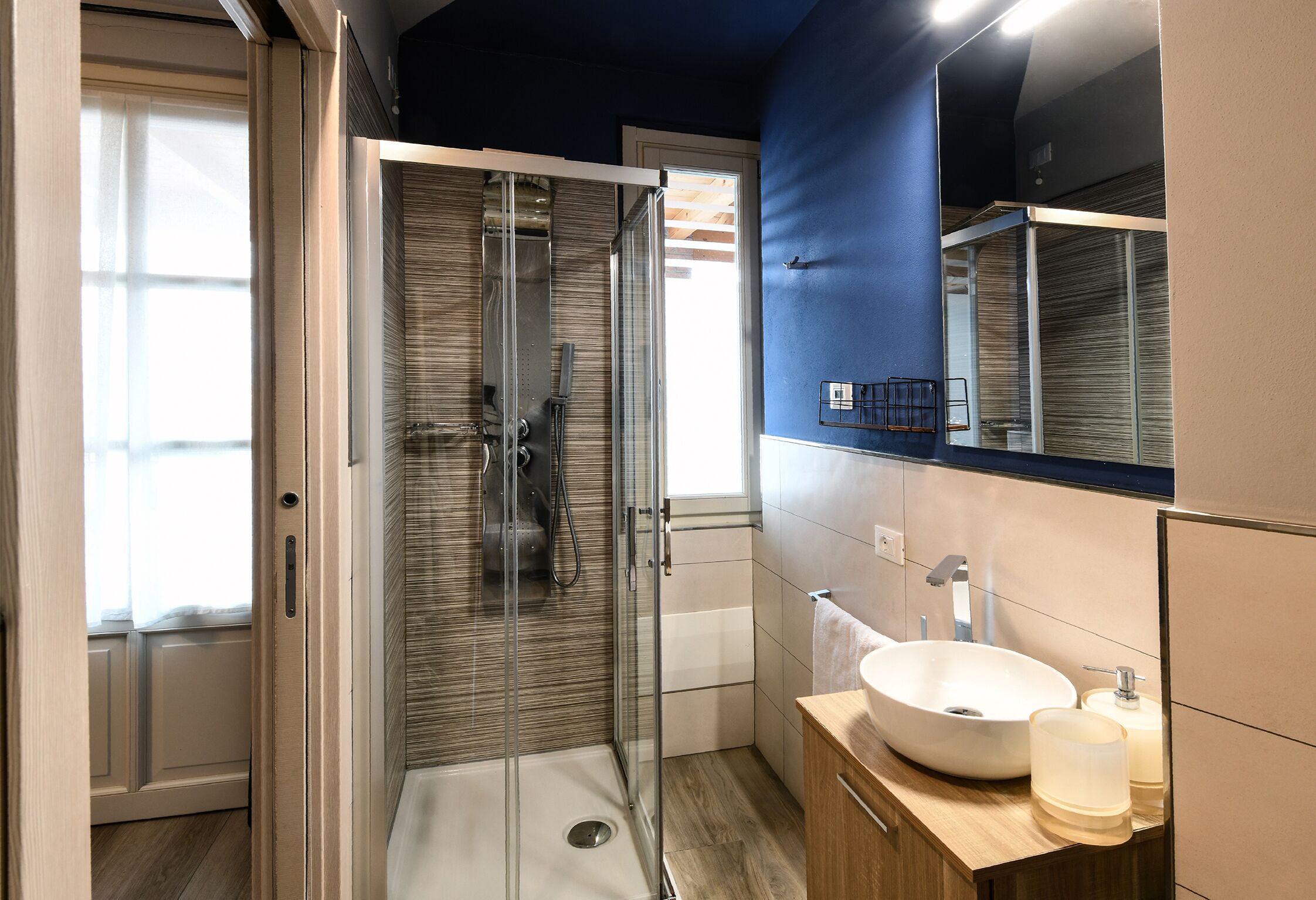 Une salle de bain moderne avec une douche à parois de verre, un lavabo avec un miroir et un meuble-lavabo en bois.