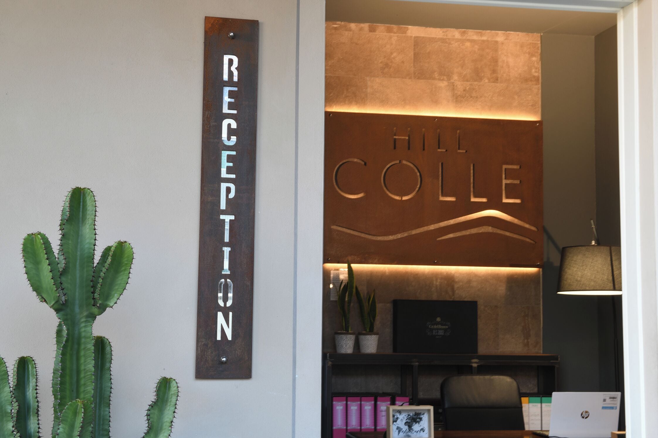 Un mostrador de recepción con un cartel que dice "RECEPTION" y "HILL COLLE" encima.