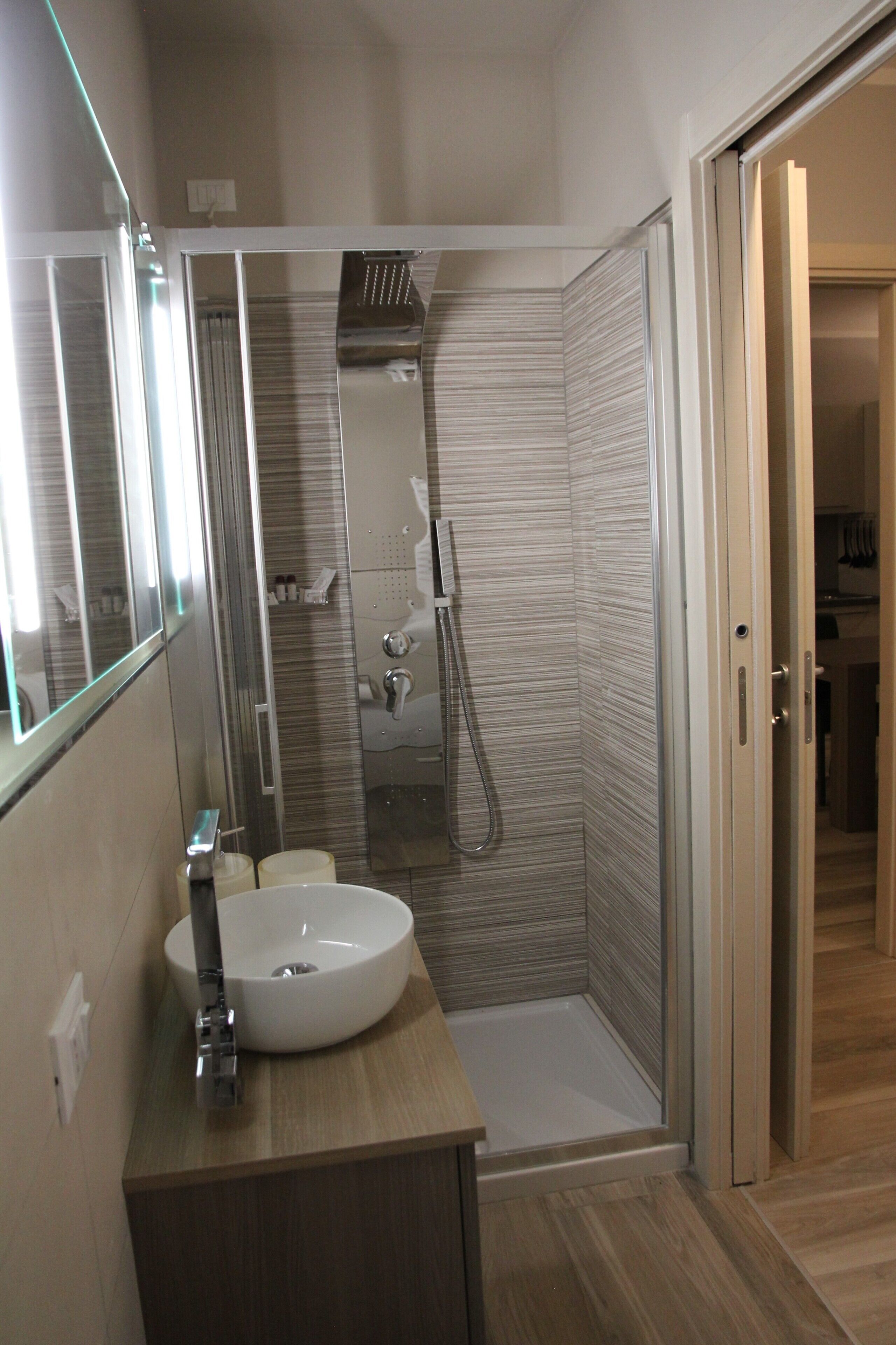 A modern bathroom with a shower, a sink, and a mirror.