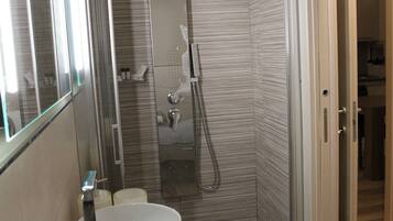 A modern bathroom with a shower, a sink, and a mirror.