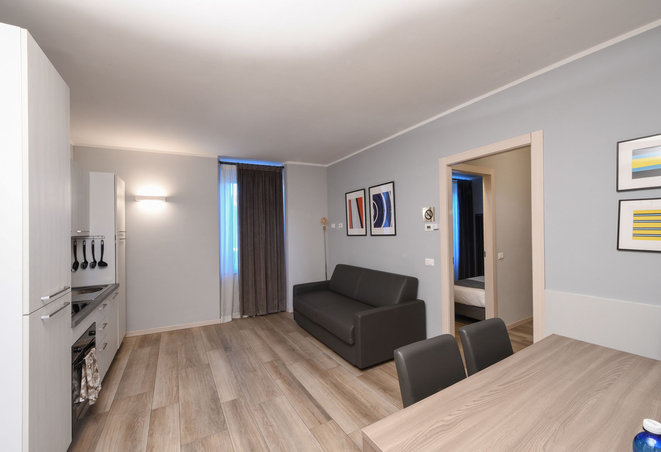 Una sala de estar moderna con un sofá, una mesa de comedor y una zona de cocina con armarios y una estufa.