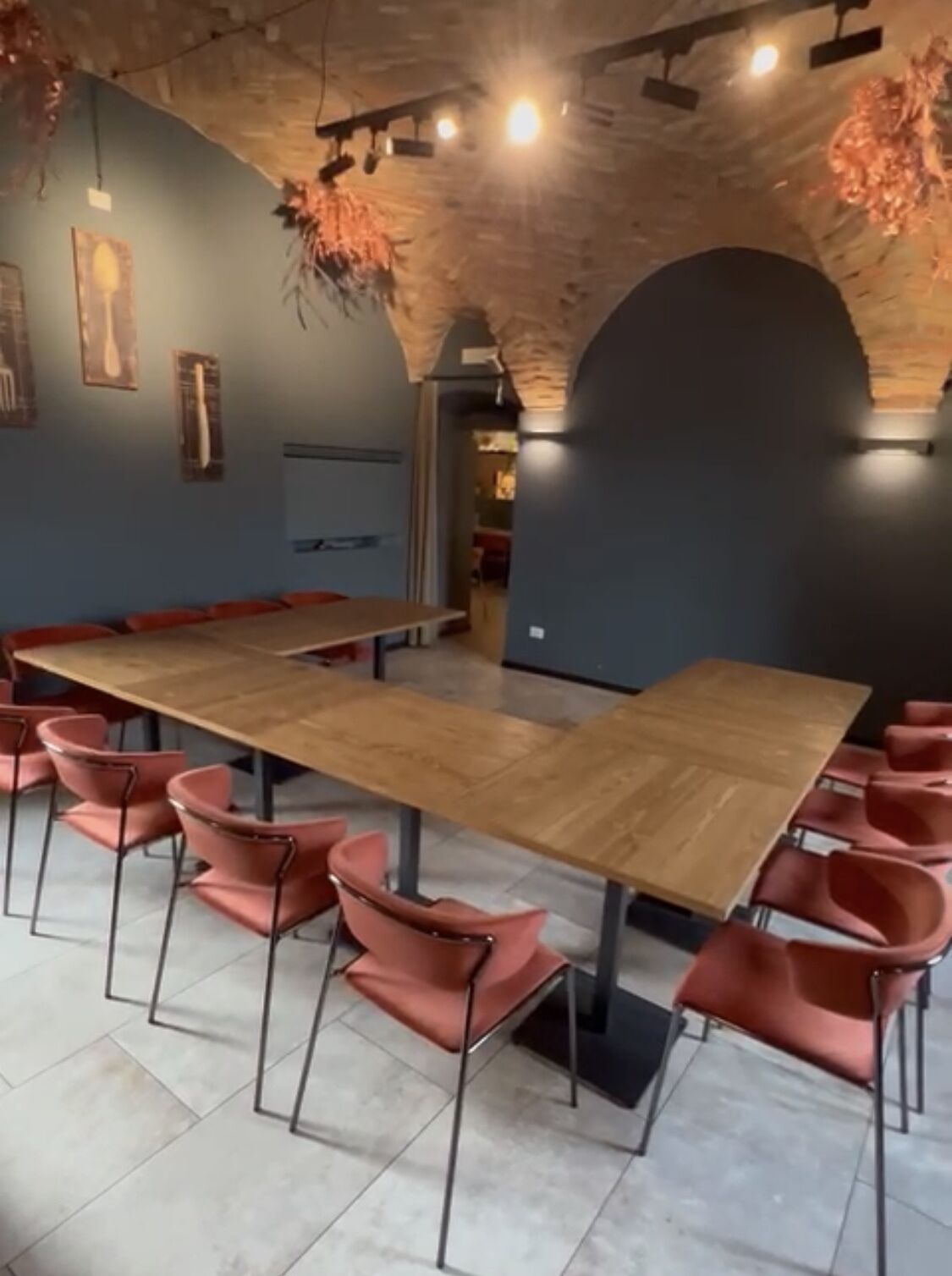 Una sala conferenze con un lungo tavolo in legno e sedie rosa, caratterizzata da pareti in mattoni a vista e illuminazione moderna.