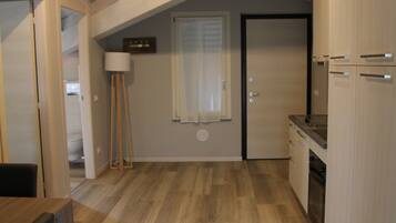 A kitchen with wooden flooring, a dining area with a table and chairs, and a ceiling with exposed beams.
