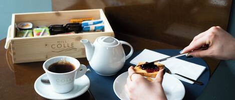 A wooden box labeled "Hill Colle" containing various items, a white teapot, a cup of coffee, and a plate with toast and jam.