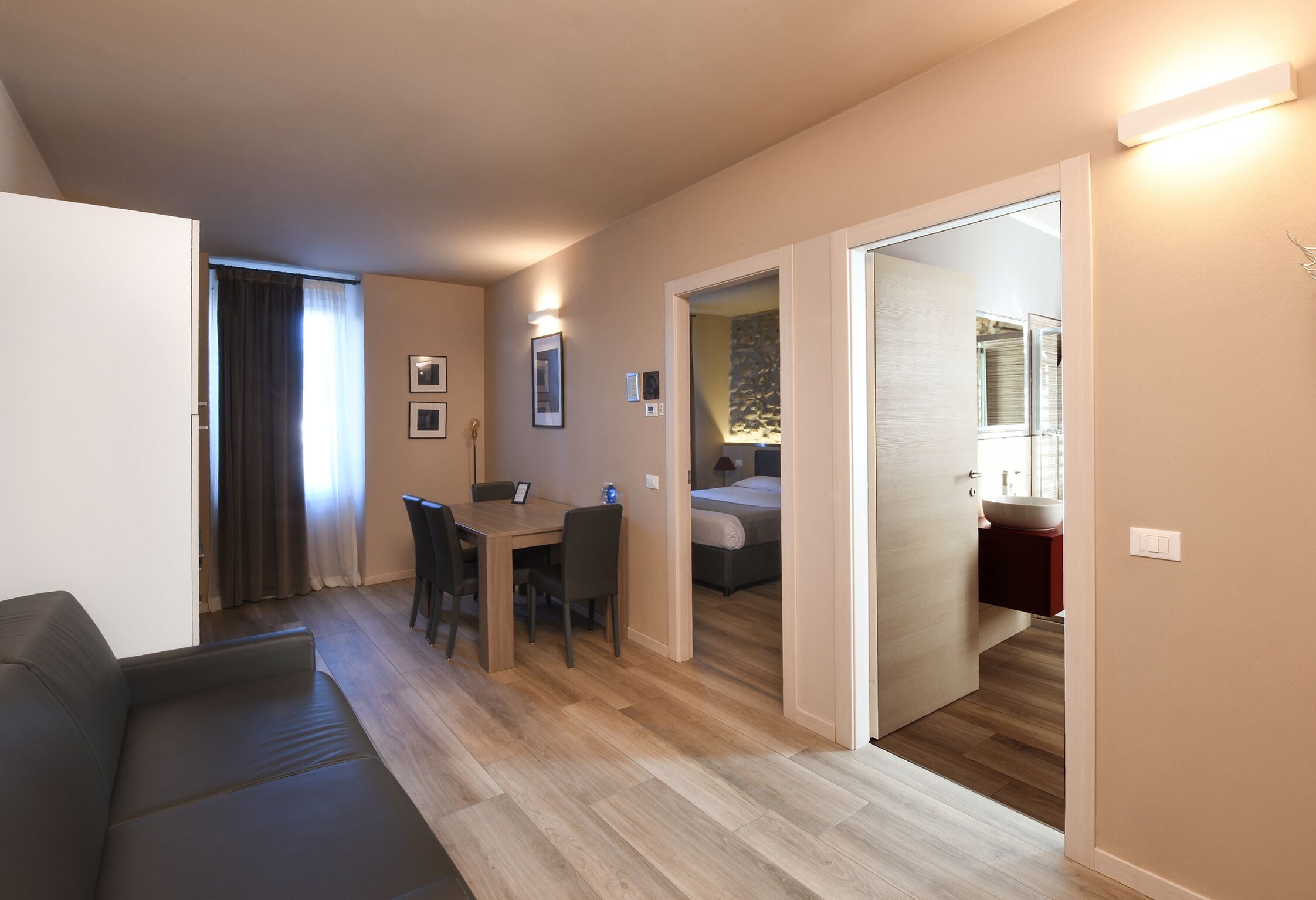 Un salon moderne comprenant un canapé, une table à manger avec des chaises et un coin cuisine avec un évier et un plan de travail.