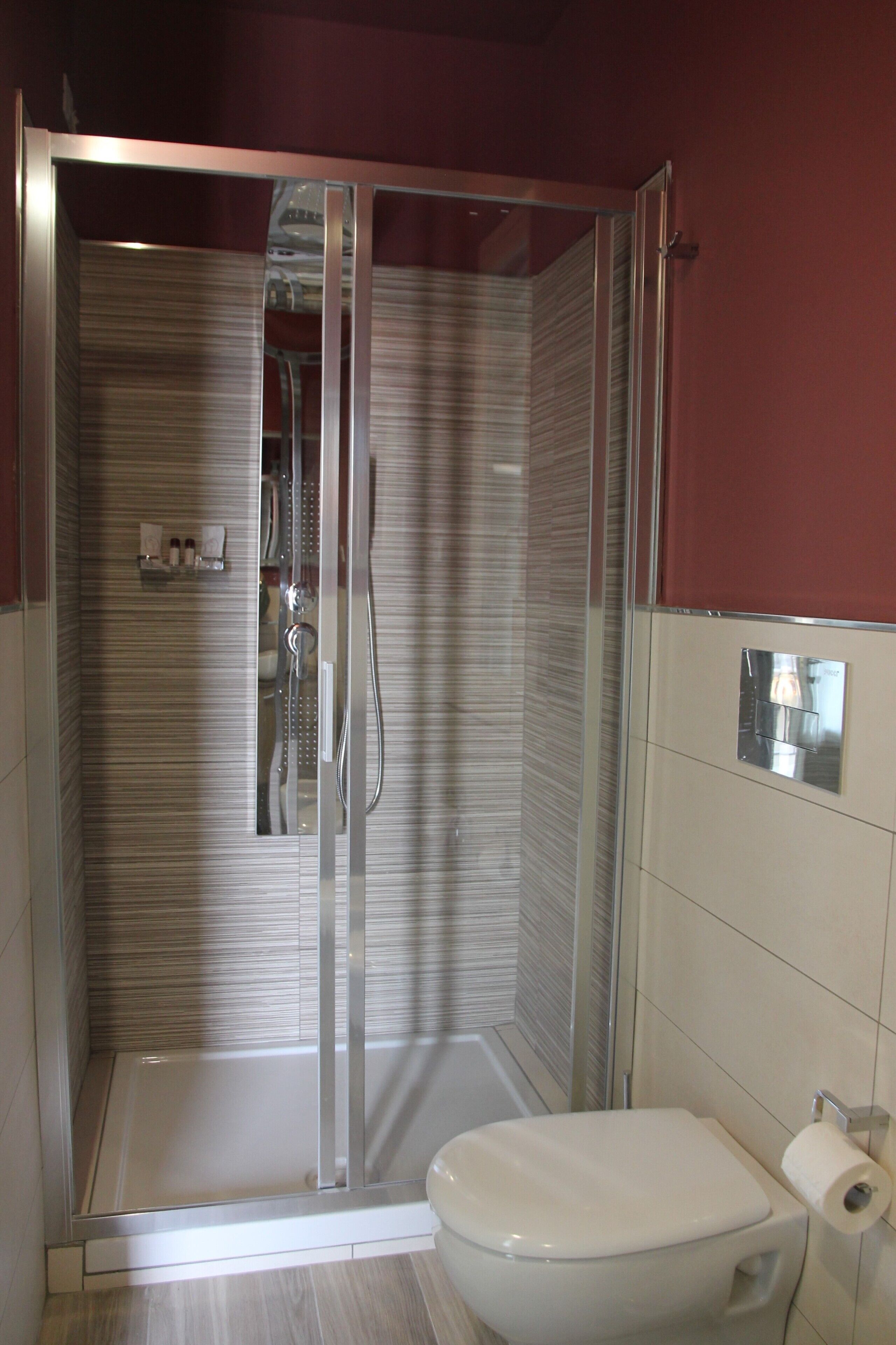Ein modernes Badezimmer mit einer Glaskabine zur Dusche, einer Toilette und einem Handtuchhalter.