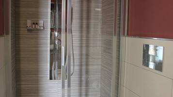 Ein modernes Badezimmer mit einer Glaskabine zur Dusche, einer Toilette und einem Handtuchhalter.