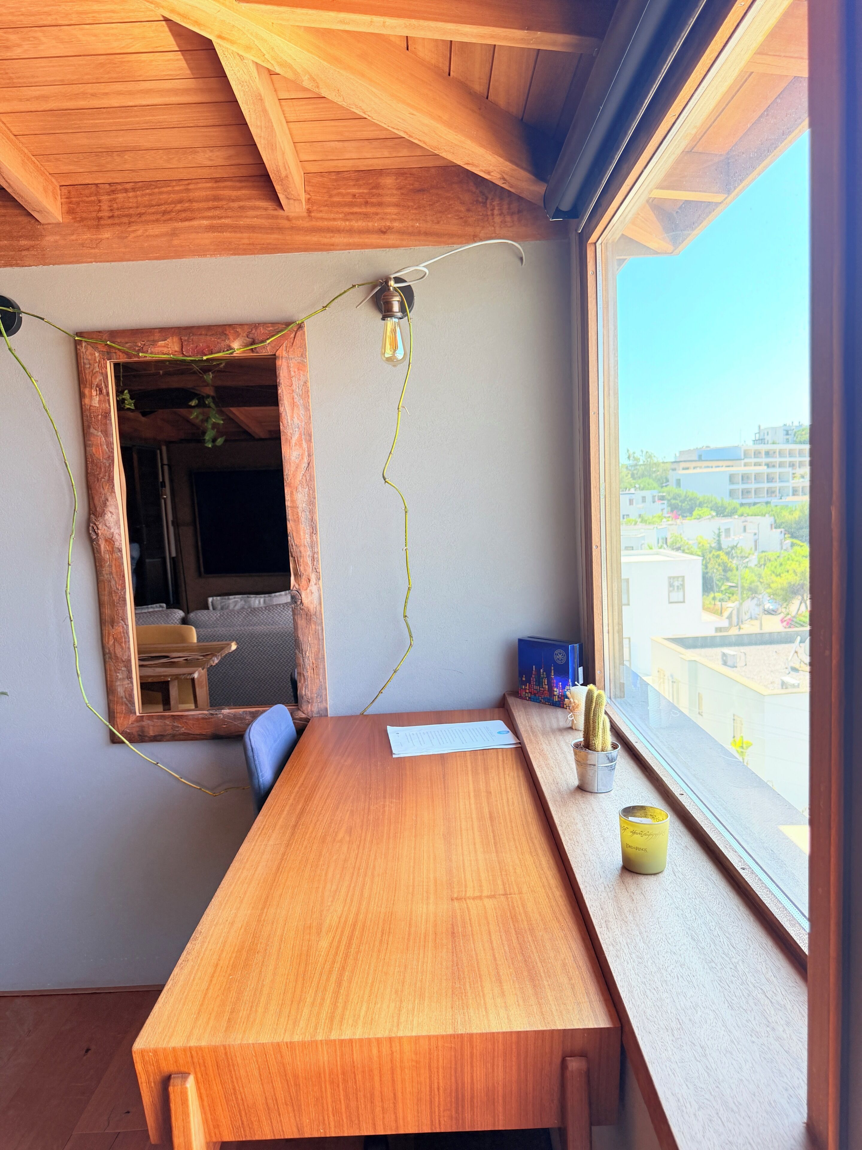 A wooden table with a view of buildings through a window.