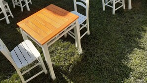 A courtyard with multiple wooden tables and white chairs arranged on a grassy area. - Yesil Konak Ayvalik (Ayvalik)
