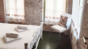 Una habitación con cama, una silla y un ventanal con cortinas.
