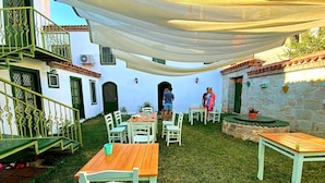 Un espacio de patio al aire libre con mesas y sillas, una escalera y un muro de piedra.