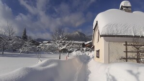 Ein verschneites Dorf mit traditioneller Architektur und einem Berg im Hintergrund.