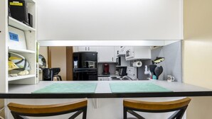 A compact kitchen with a central island, white cabinets, and a microwave. - Whitman Point Townhome Unit A is Gulf Front with Sunsets & fishing pier (Cedar Key)