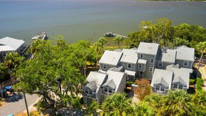 A coastal property with multiple houses, a dock, and a boat. - Whitman Point Townhome Unit A is Gulf Front with Sunsets & fishing pier (Cedar Key)