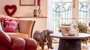 Un salon chaleureux avec un canapé, un cœur décoratif, une petite statue d’éléphant et une table sur laquelle se trouvent une bougie et un récipient en verre.