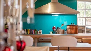 Une cuisine avec un dosseret de couleur turquoise, des casseroles en cuivre et un fourneau moderne.