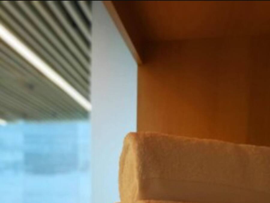 A stack of white towels on a wooden surface in a room with a view of a pool area.