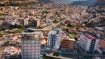 A cityscape with modern buildings, a mix of residential and commercial structures, and a mountainous backdrop.