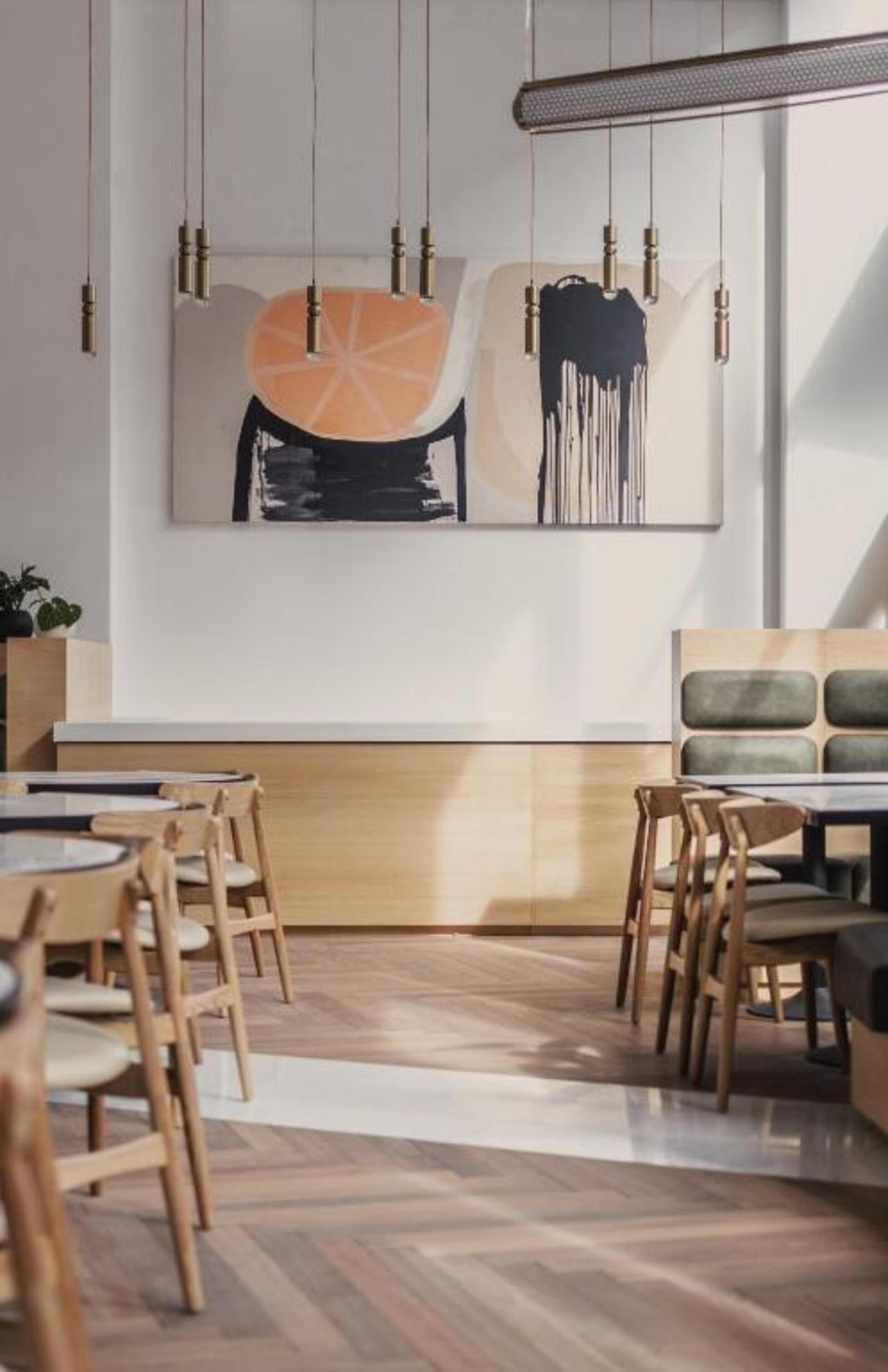 A modern dining area with wooden chairs, a long table, and a large abstract painting on the wall.
