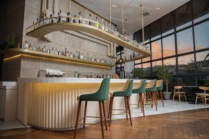 Zona de bar con una barra curva, varios taburetes y un amplio ventanal con vistas al exterior.