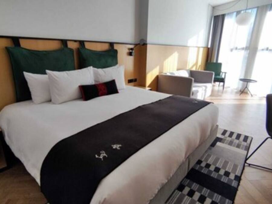 Een hotelkamer met een groot bed, een bureau, een stoel en uitzicht op de omgeving.