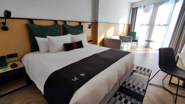 A hotel room with a large bed, a desk, a chair, and a view of the outdoors. - MET Hotel (La Paz)