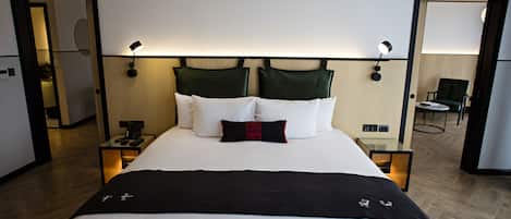 A hotel room with a large bed, bedside lamps, a nightstand, and a chair in the corner.