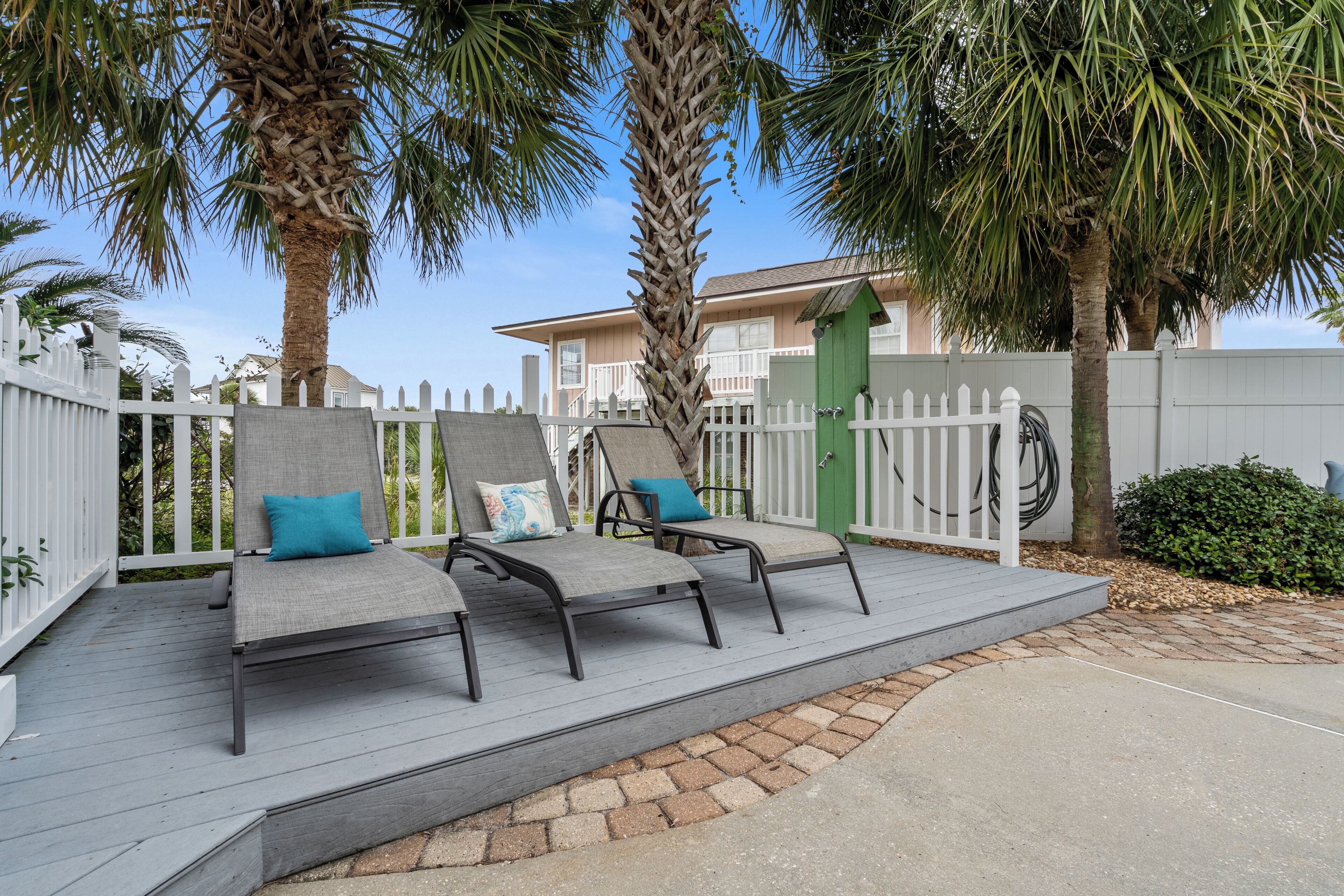 A wooden deck with three grey lounge chairs, each with a cushion.