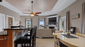 A modern kitchen with a dining area, a ceiling fan, and a TV. - Southern Peach East Beach House 3BD Private Pool Boat Dock (Pensacola)