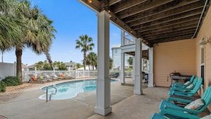 A pool area with lounge chairs, a barbecue setup, and a covered patio with wooden beams. - Southern Peach East Beach House 3BD Private Pool Boat Dock (Pensacola)
