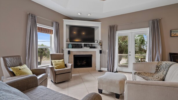 A living room with a fireplace, comfortable seating, a flat-screen TV, and large windows with curtains. - Southern Peach East Beach House 3BD Private Pool Boat Dock (Pensacola)