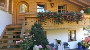 A wooden building with a balcony, a staircase, and a small Christmas tree. - Ferienwohnung 1, 90 qm, Eigener Eingang, mit Terasse, 4 Sterne (Samerberg)