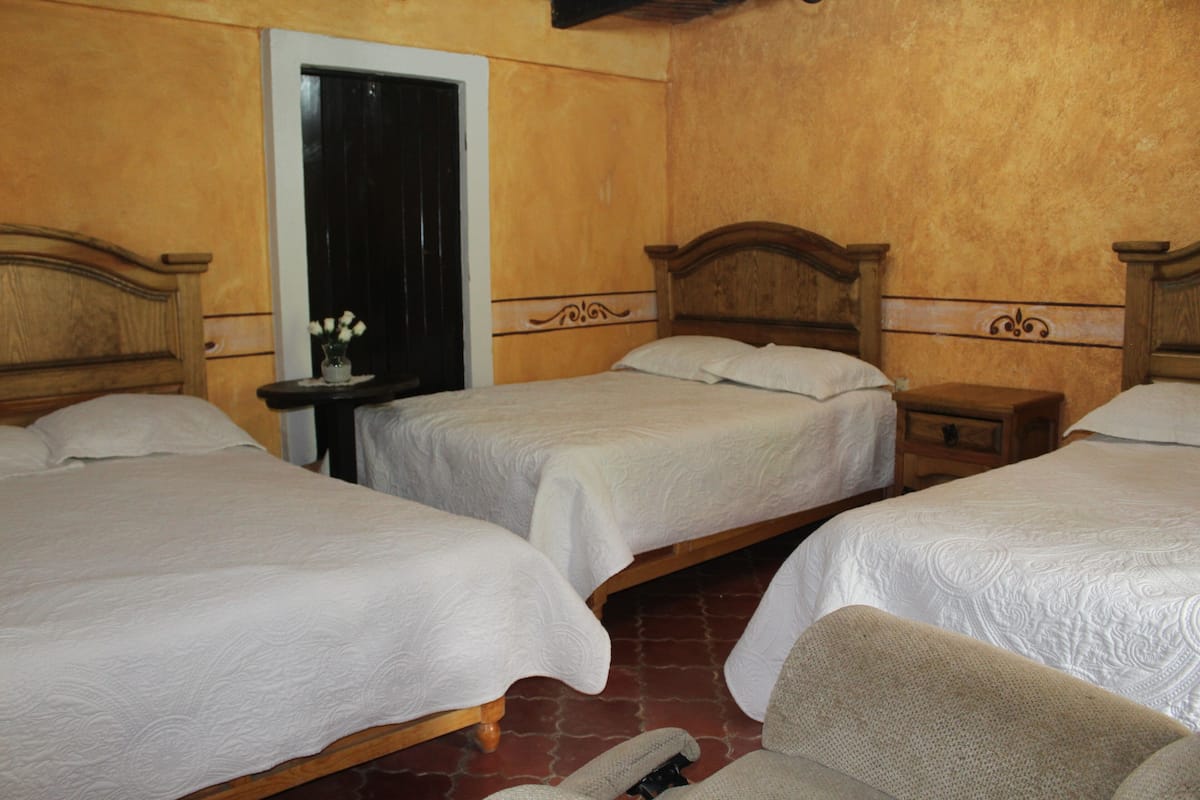 A hotel room with two single beds, a nightstand, and a chair.