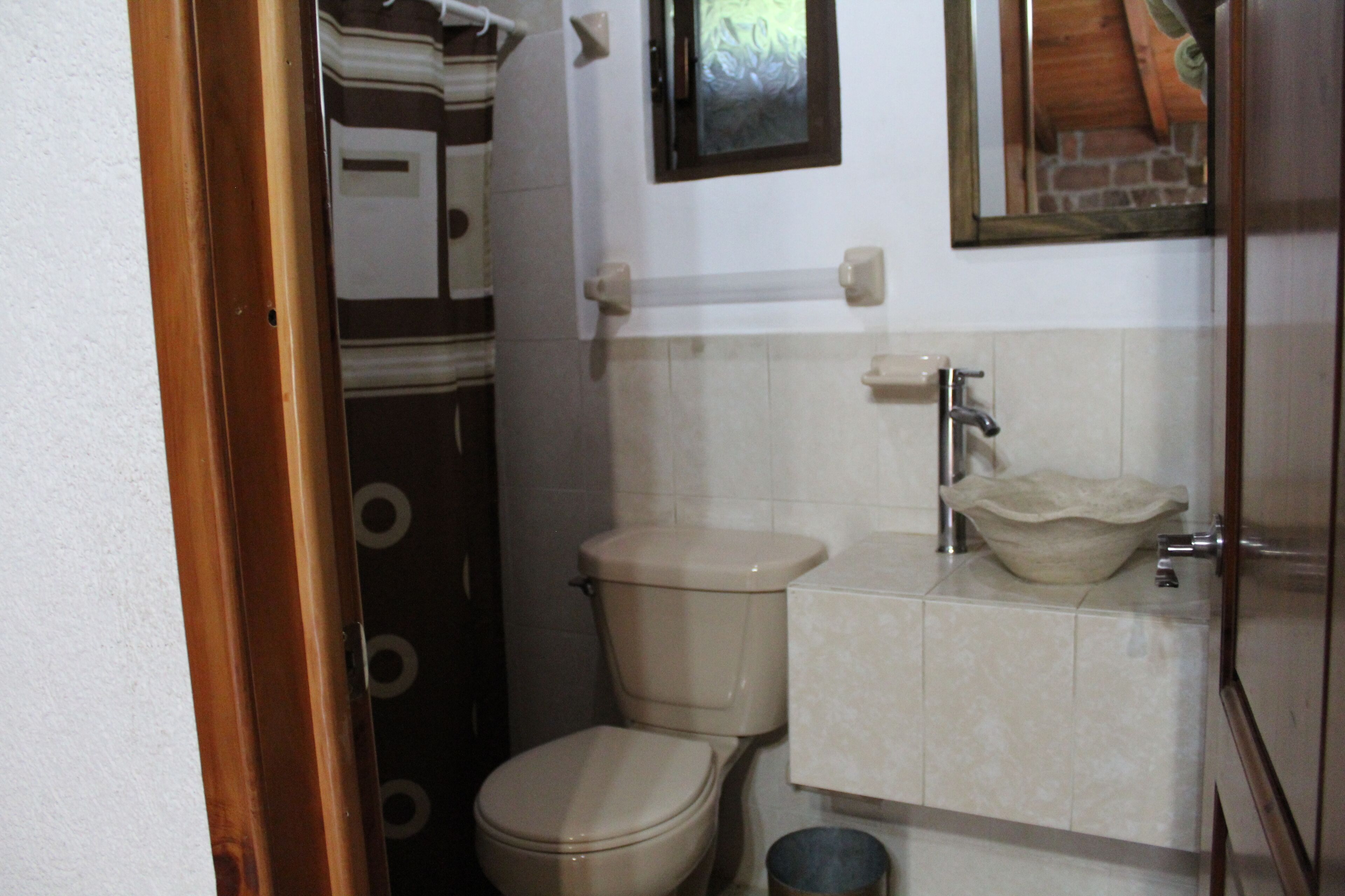 Un baño con inodoro, lavamanos y espejo en la pared.