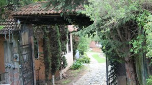 A stone pathway leading to a gated entrance with a tiled roof and ivy-covered walls. - Cabañas Esperanza (Tlalpujahua)