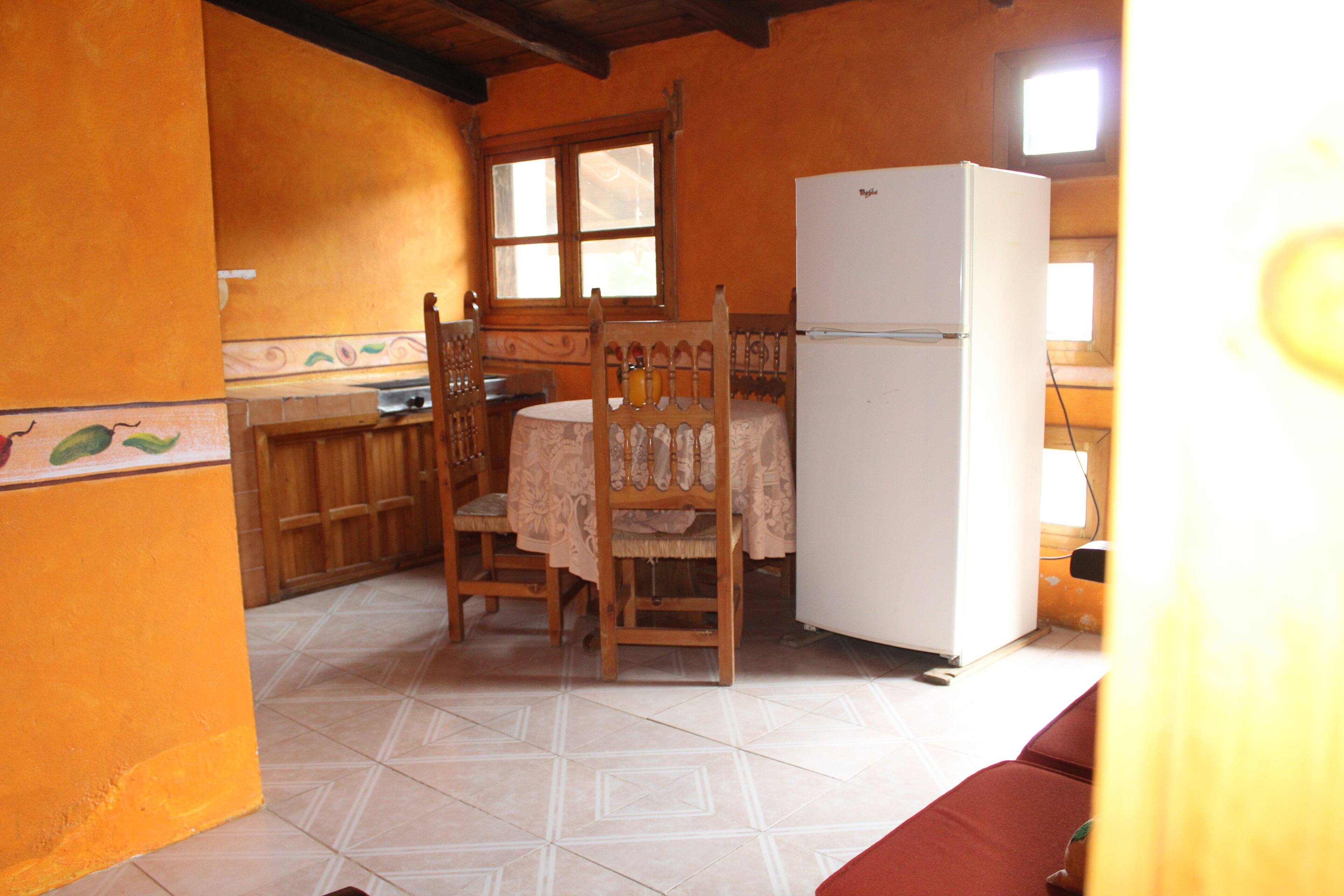 A kitchen with a dining table, chairs, a refrigerator, and a window.