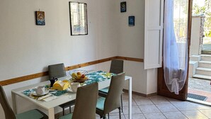 Ein Essbereich mit einem Tisch für vier Personen, Stühlen, einer Hängelampe und einer Tür, die nach draußen führt.