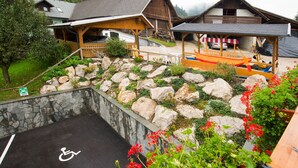 A rustic mountain lodge with a wheelchair-accessible parking area, stone walls, and a wooden boat. - Penzion Pr Anzl (Bled)