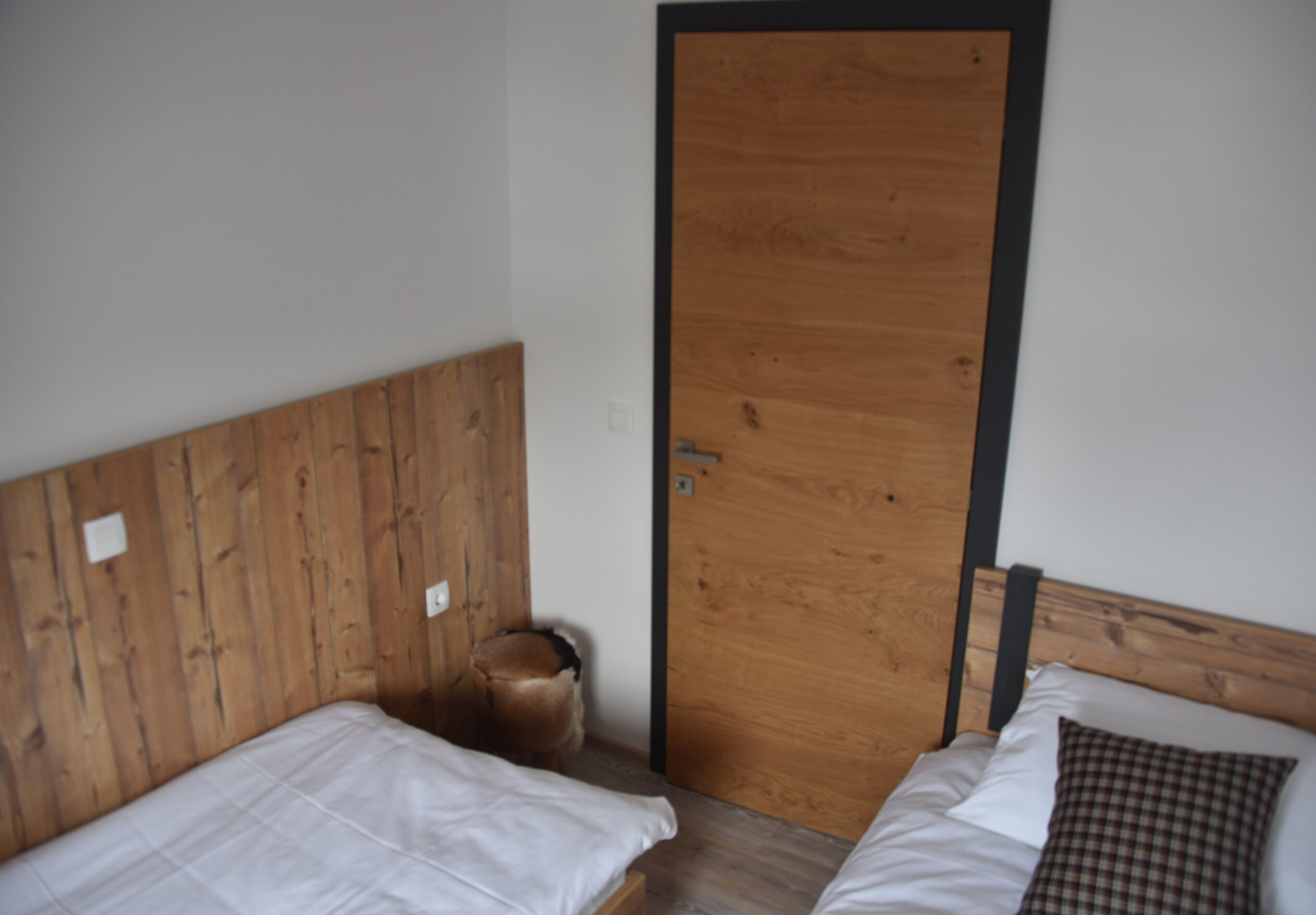 Un dormitorio con dos camas, cabeceros de madera y una puerta de madera.